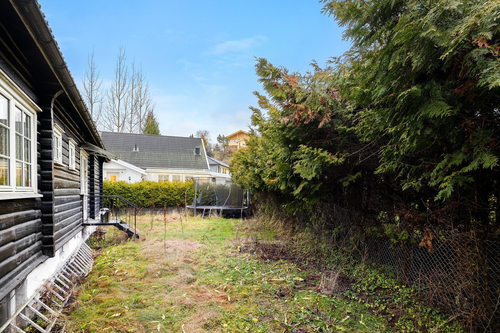 Fra kjøkkenet er det egen utgang til en romslig og barnevennlig bakhage. Gressplenen strekker seg langs både baksiden og venstre side av boligen, og gir rikelig med plass til lekestativ, trampoline eller annen uteaktivitet Galleribilde