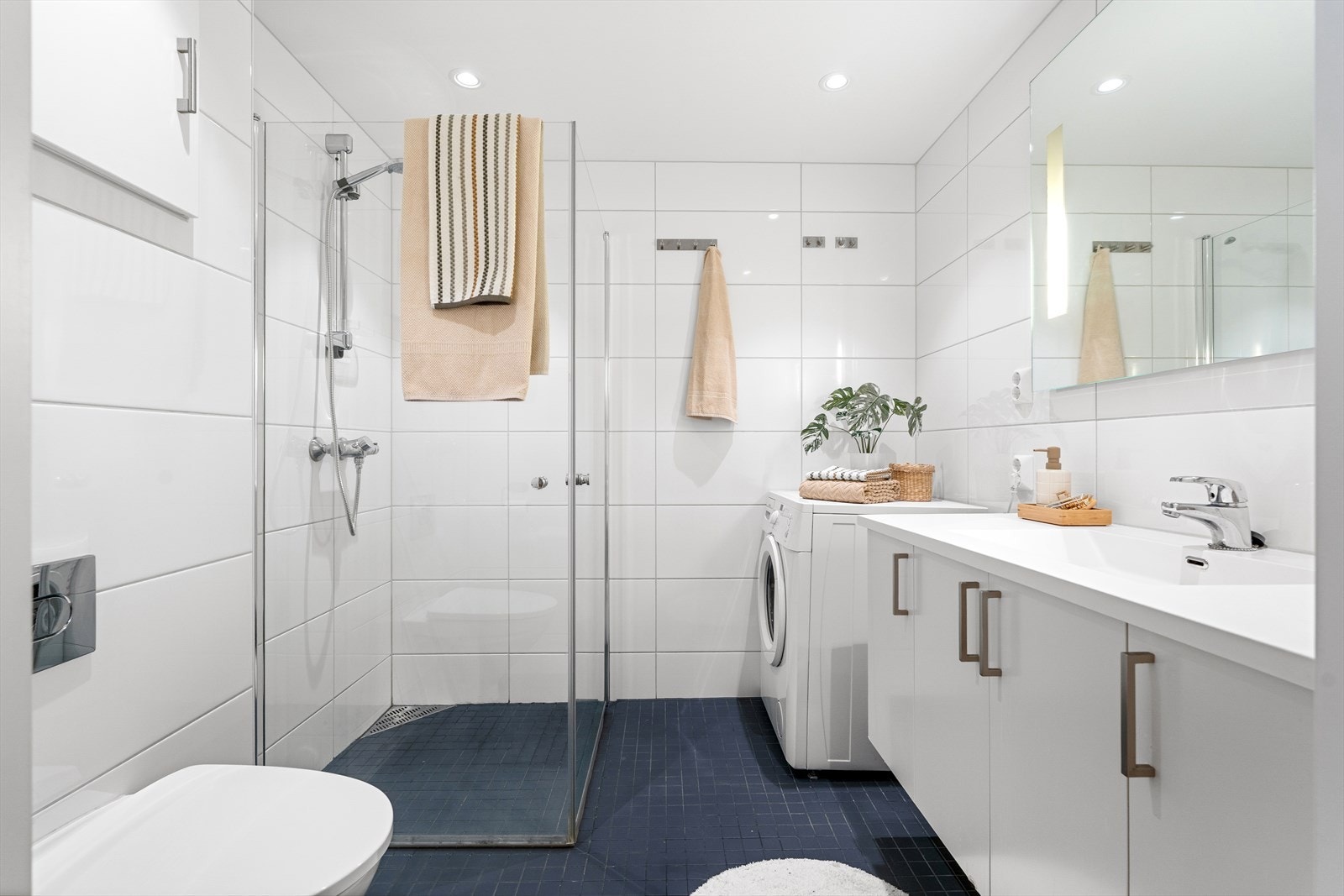 Det 4 m² store badet fremstår som innbydende med helflisede overflater, behagelig gulvvarme og downlights i tak. Galleribilde
