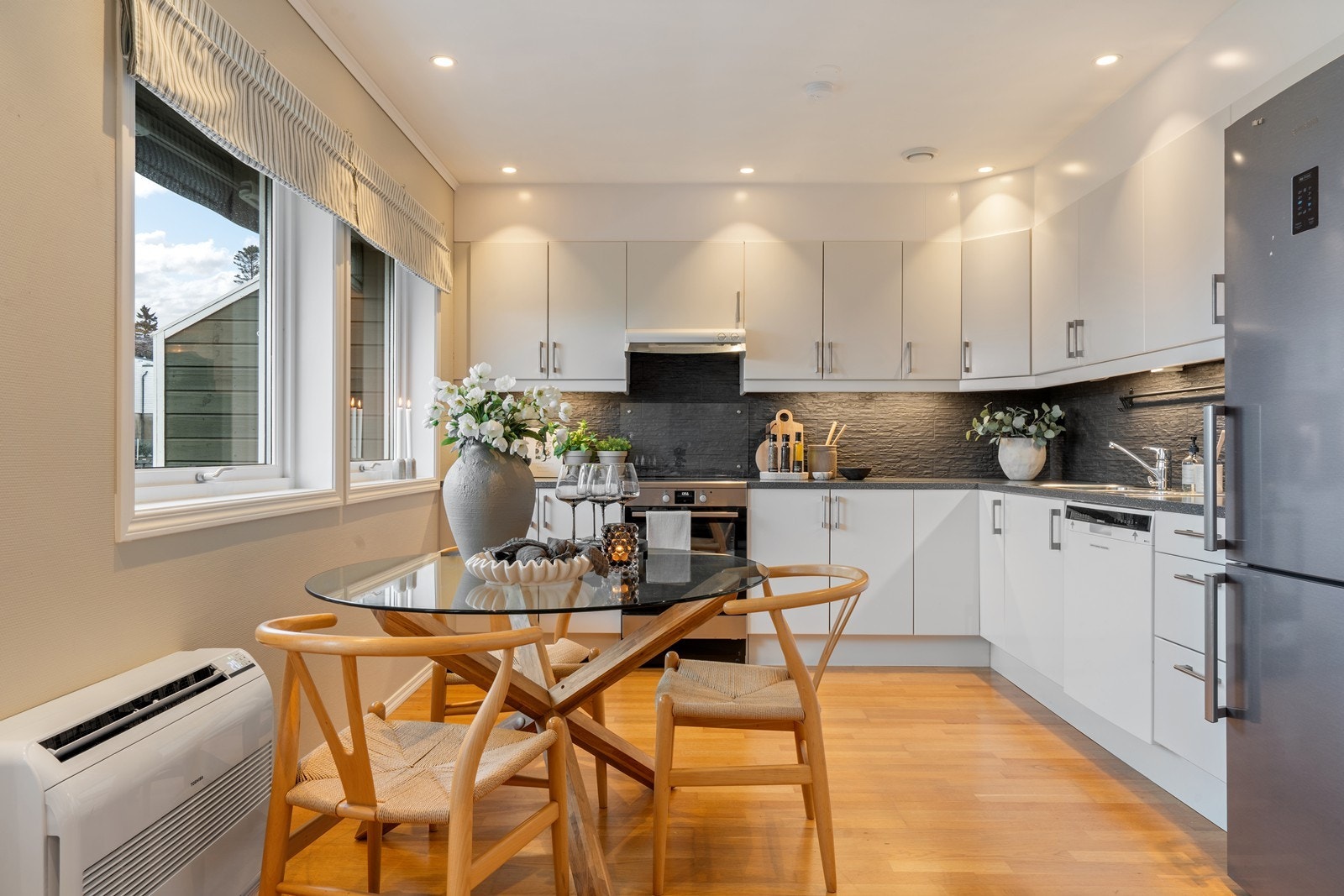 Kjøkken med spotter i tak, fliser over benk og nyere varmebumpe type gulvmodell Galleribilde