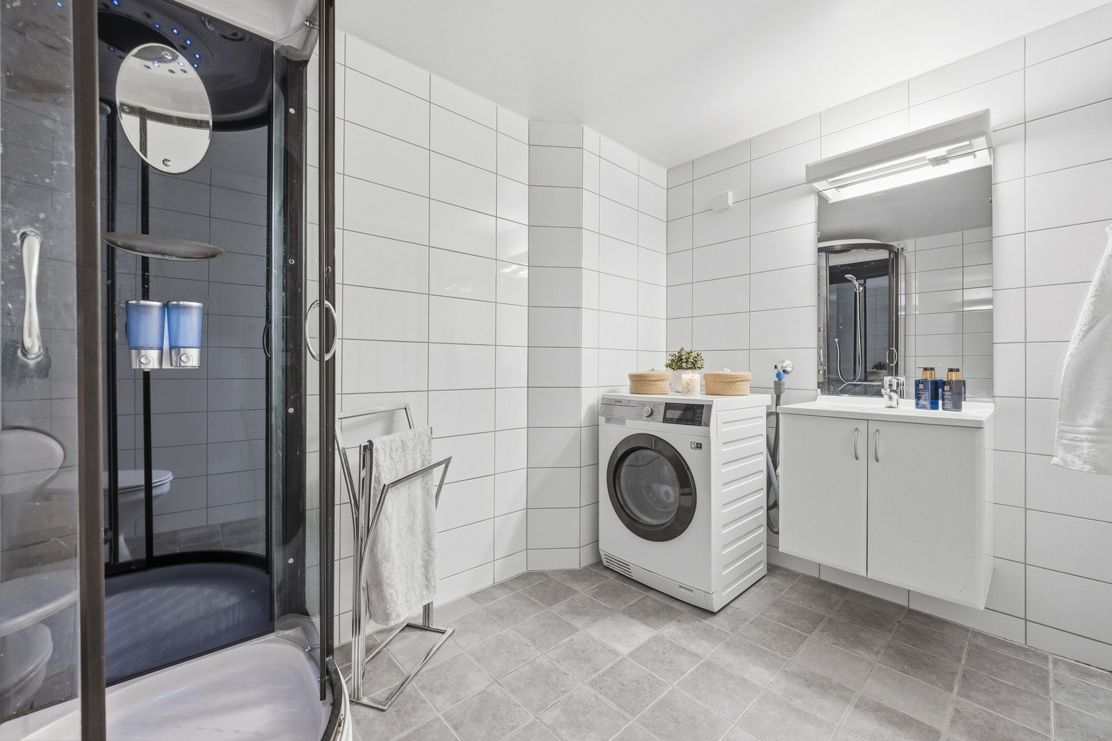 Stort, praktisk flislagt baderom med opplegg for vaskemaskin. Galleribilde