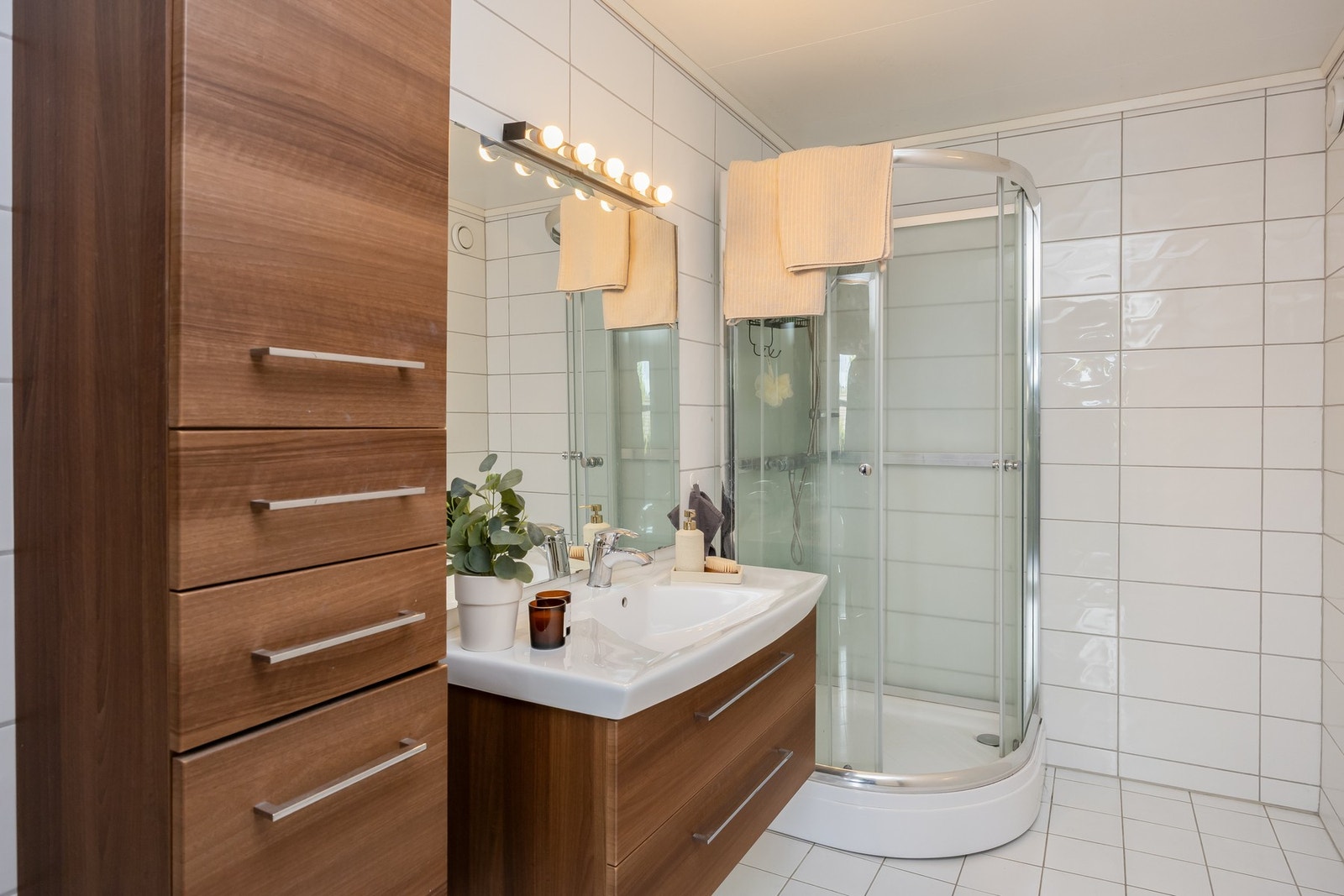 Flislagt bad i hybelen med rikelig lagringsplass, servant og dusjhjørne med innfellbare dører. Gulvvarme. Galleribilde