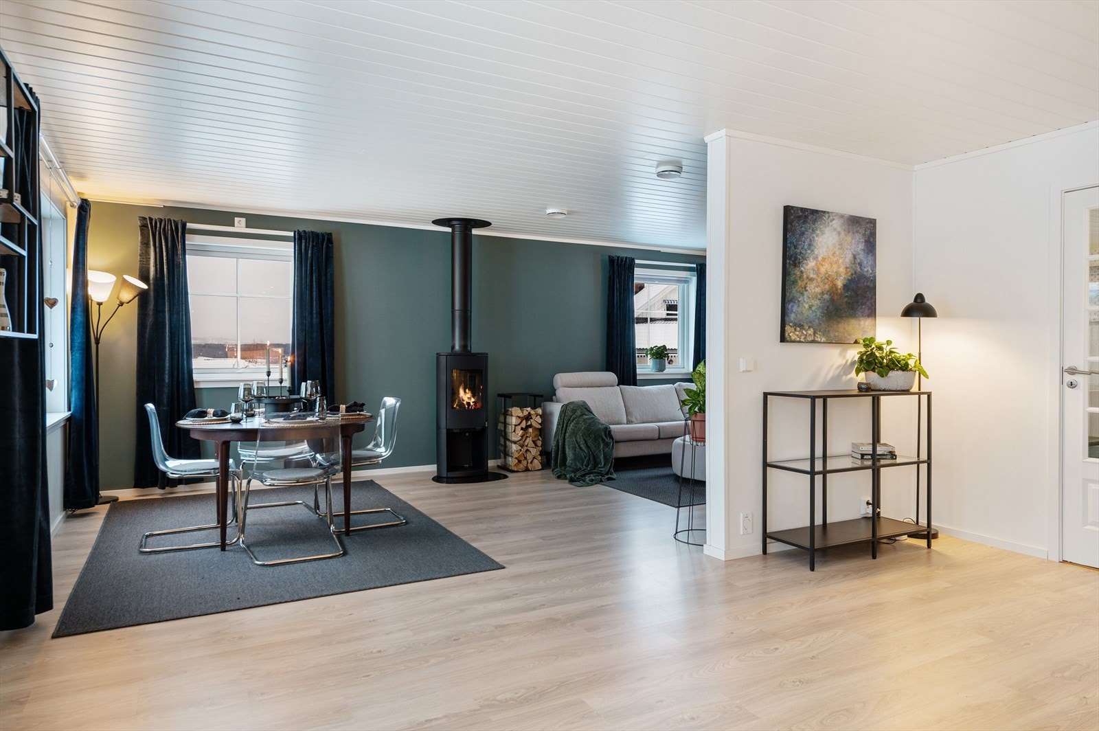 Stuen er i vinkel og deles fint inn i funksjonelle soner. Koselig peisovn mellom spisestue og sofaområdet. Galleribilde