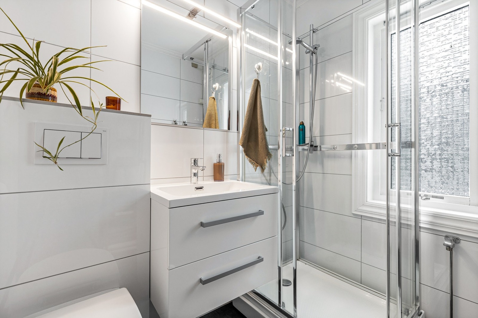 Rommet har innredning med nedfelt servant, veggmontert toalett, dusjkabinett og opplegg for vaskemaskin Galleribilde