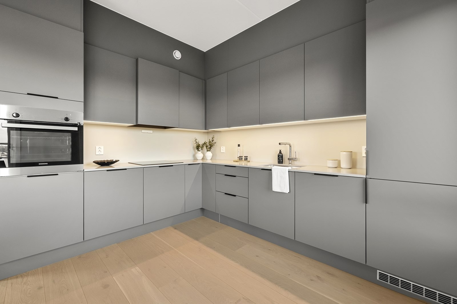 Moderne kjøkken med glatte, håndtaksløse fronter og rikelig med skap- og benkeplass. Galleribilde