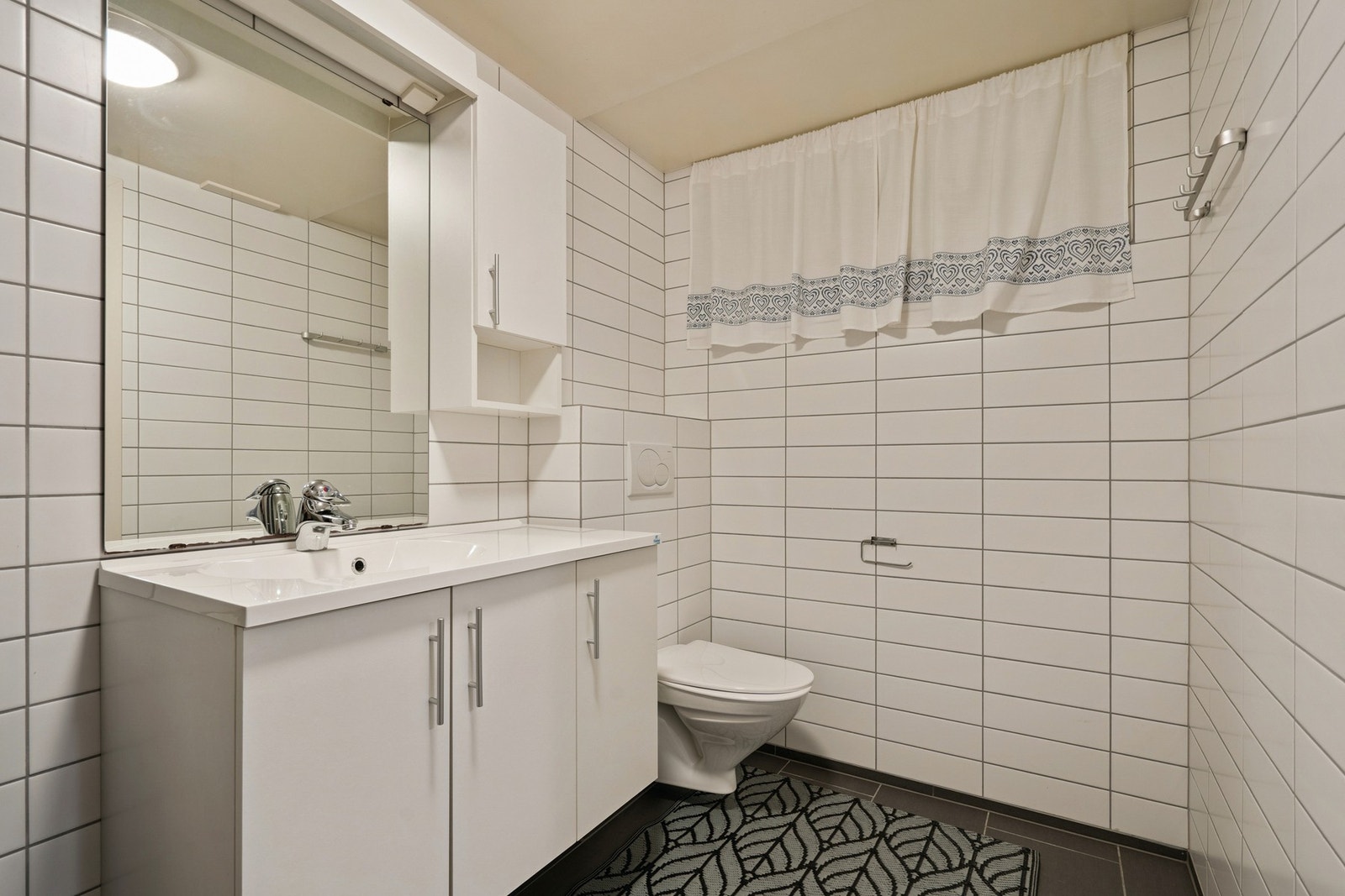 Rommet er innredet med vegghengt toalett, servant på møbel og dusjarmatur. Galleribilde