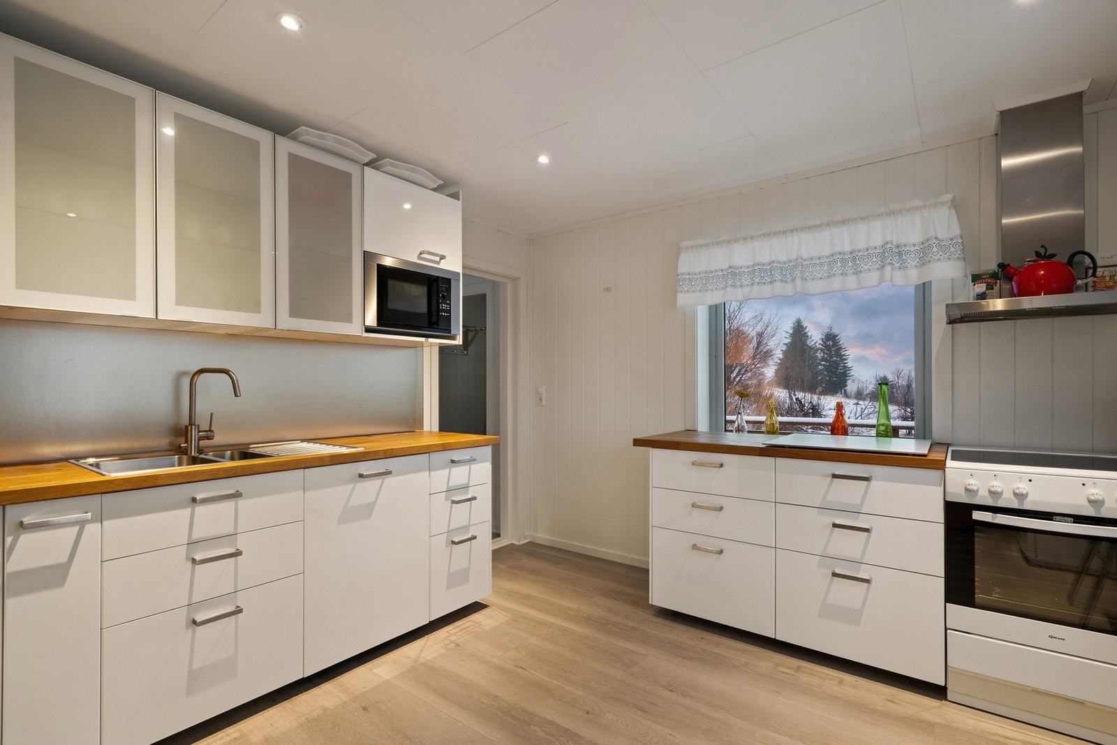 Kjøkkeninnredning med hvite fronter og heltre benkeplate av eik. Galleribilde