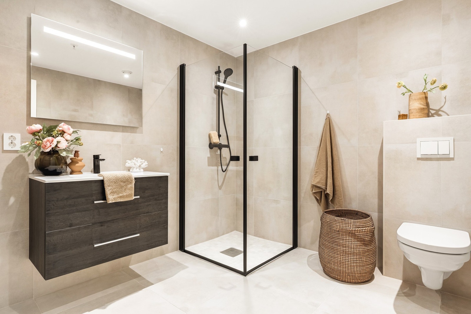 Badet er helfliset med 60x60 fliser og har lekre sorte detaljer som setter et moderne preg på badet! Det er også spotlights i himling og varmekabler i gulv. Galleribilde