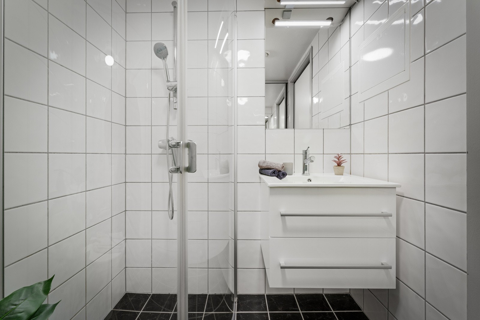 Utstyr: Foldedører i dusj, veggtoalett og baderomsinnredning med heldekkende servant samt belyst speil Galleribilde