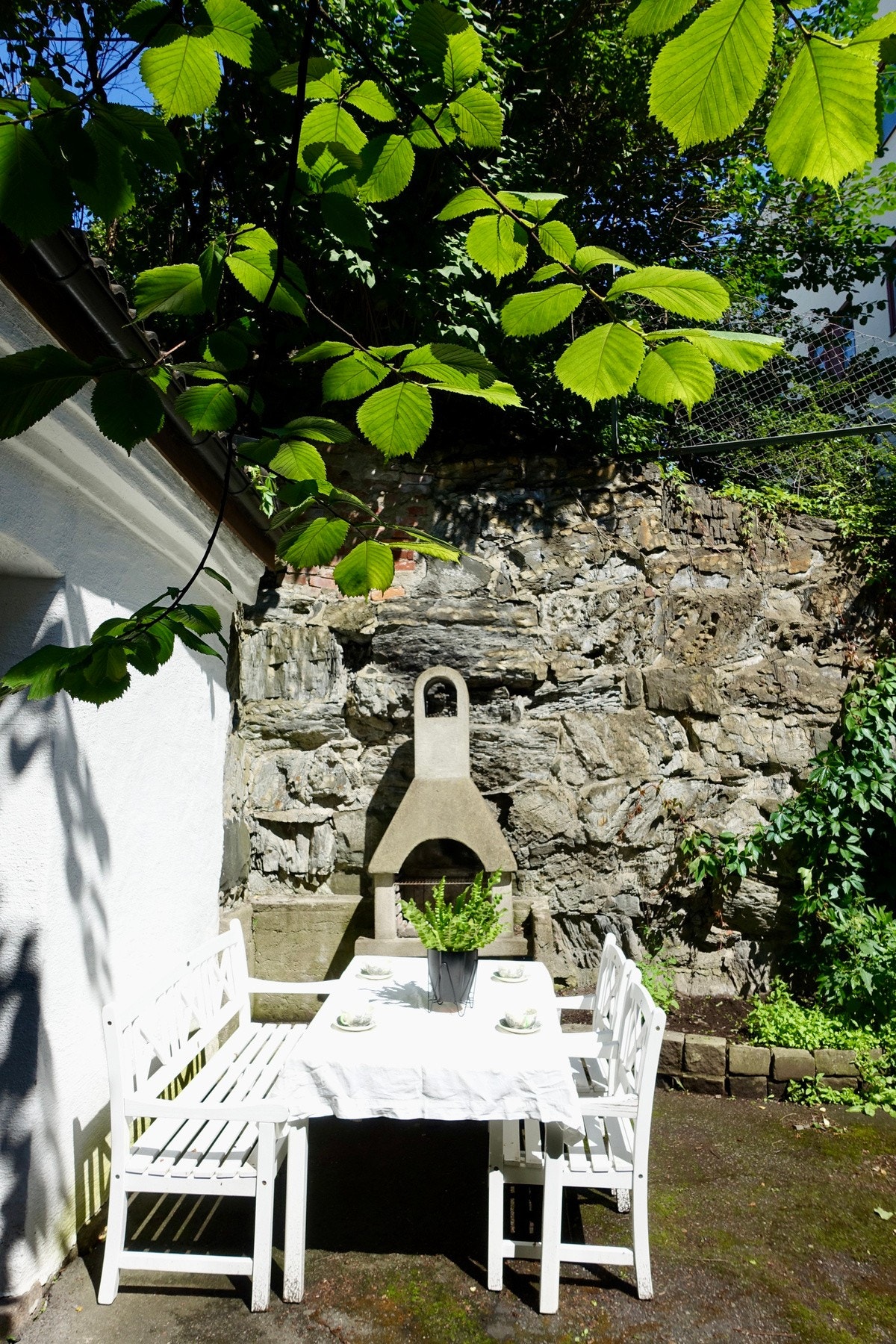 Pent opparbeidet og skjermet bakgård med hyggelige sittegrupper, peis og beplantning. Galleribilde