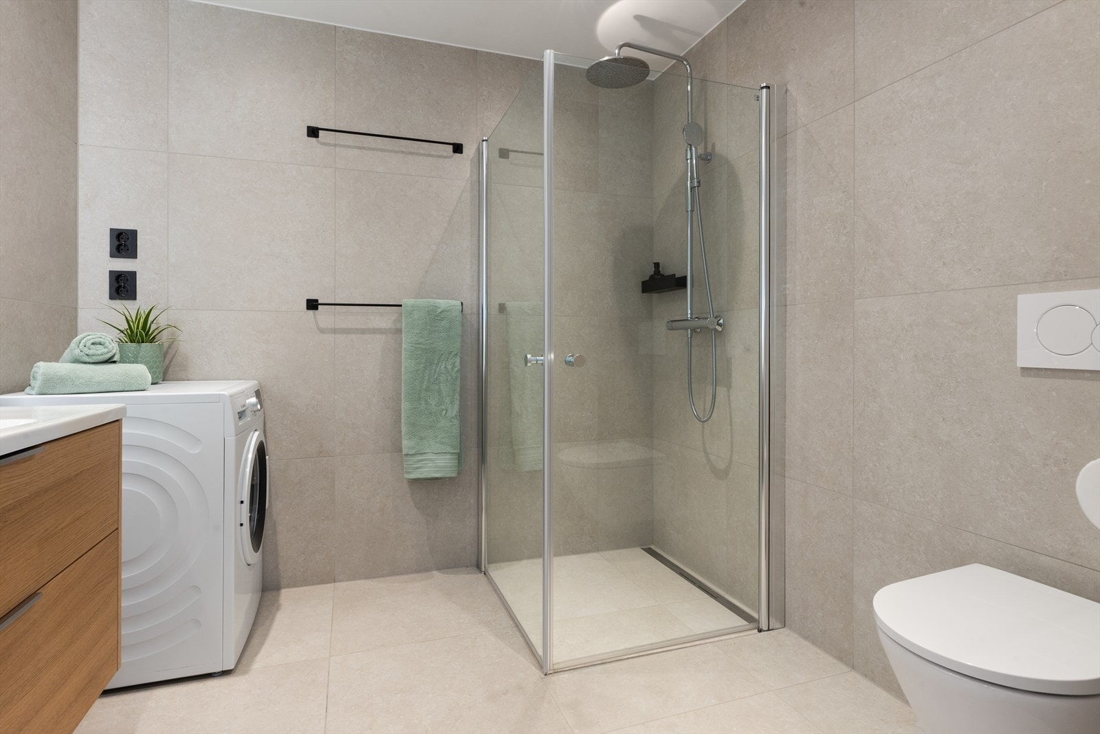 Dusjhjørne med innfellbare glassdører og elegant slukrenne ved veggen. Galleribilde