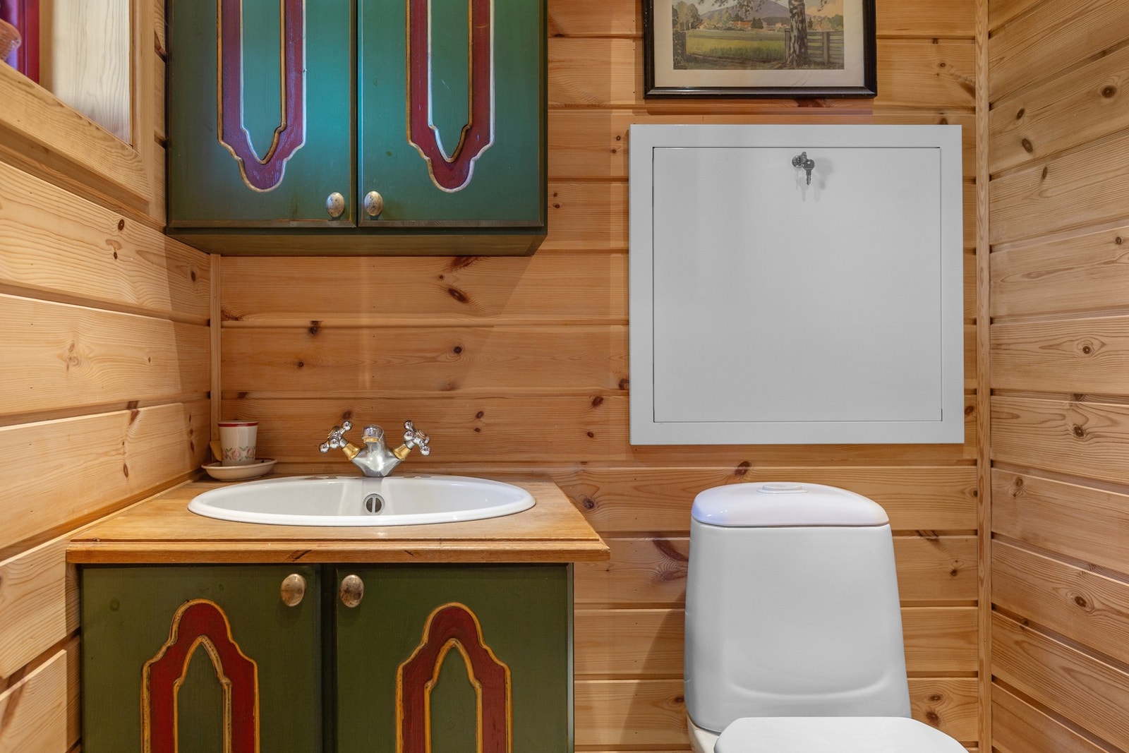 Toalettrom har gulv belagt med fliser, vegger og himling er kledd med trepanel.
Montert klosett og servant. Galleribilde