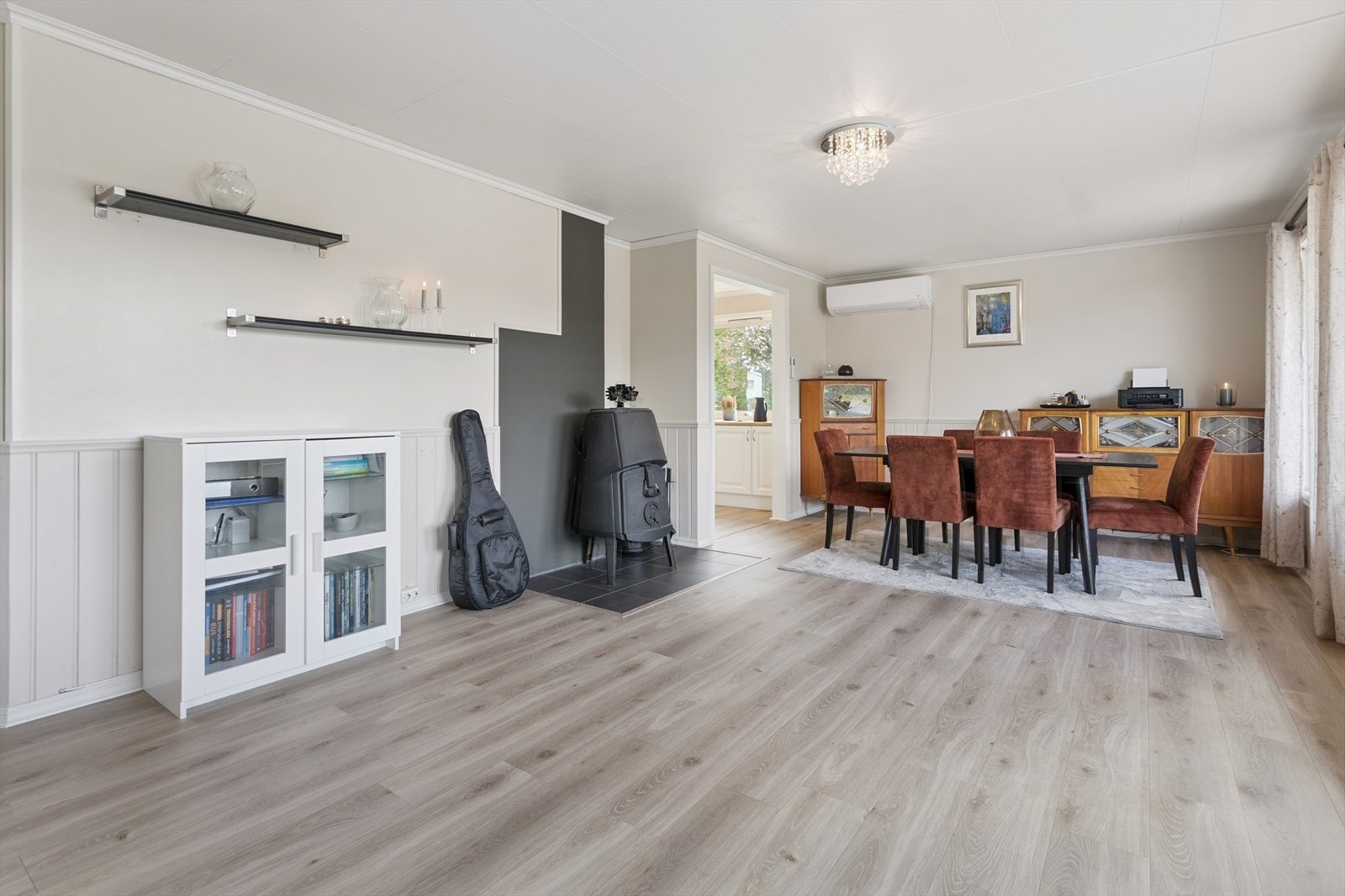 Stuen er romslig og har en åpen løsning mot spisestuen, med en eldre vedovn som gir ekstra varme. Galleribilde