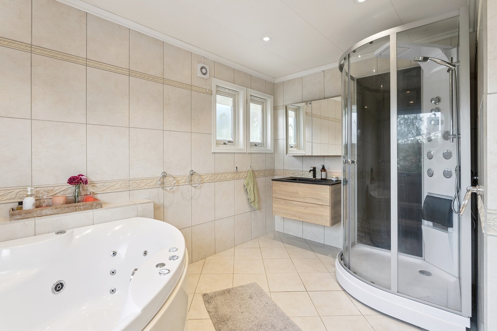 Badet i første etasje er helfliset og utstyrt med både dusjkabinett og boblebadekar. Galleribilde