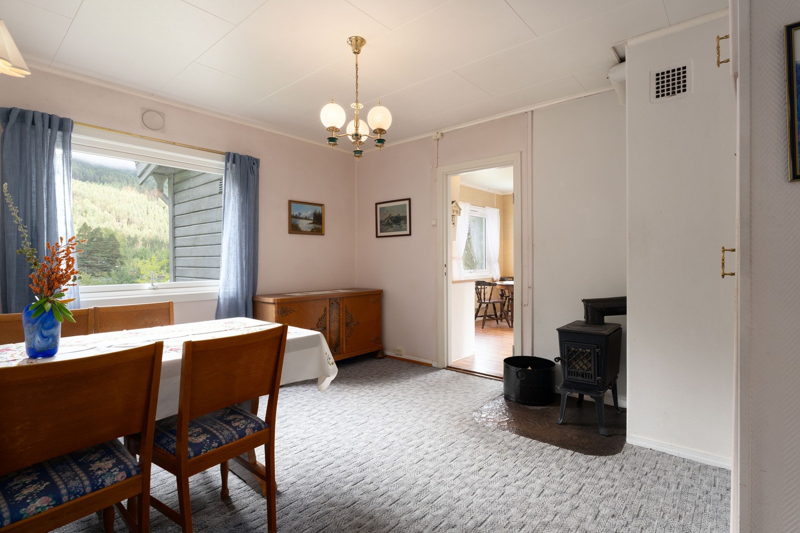 Spisestuen er fint plassert mellom gang og kjøkkenet. Her er det også en egen vedovn. Rommet har tidligere vært i bruk som et soverom. Galleribilde