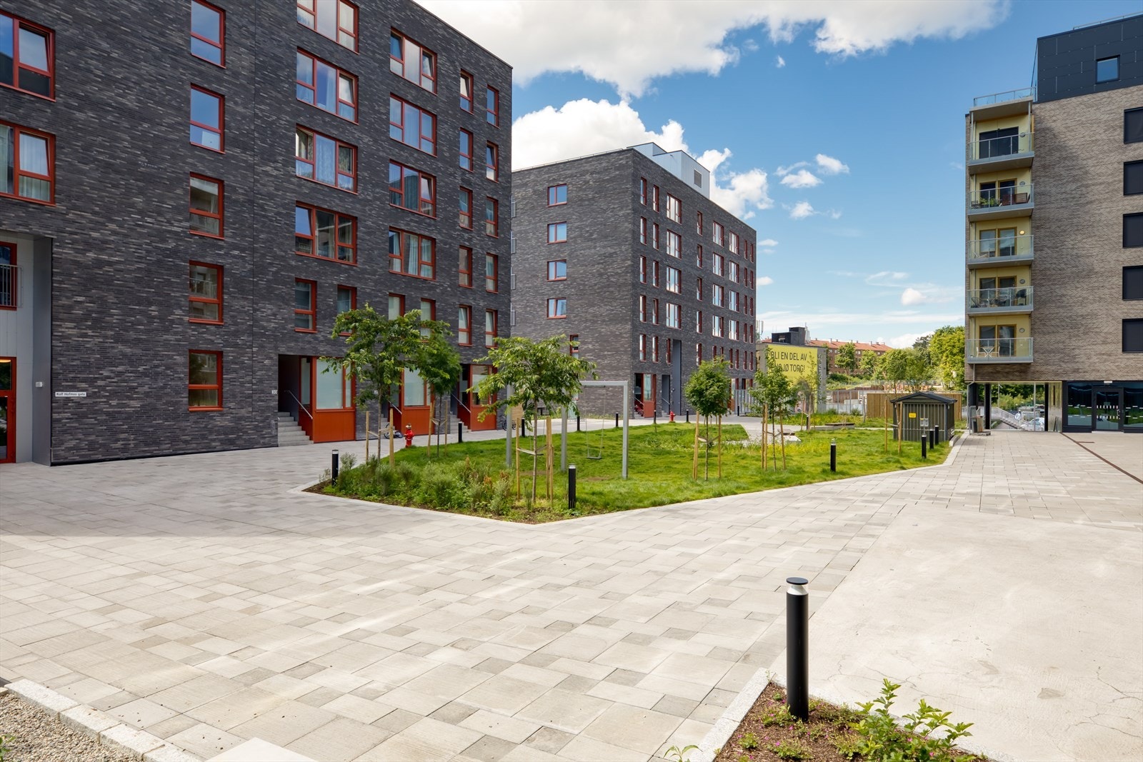 Inngangspartiet til leilighetsblokken er omkranset av bilfritt tun med en hyggelig lekeplass. Galleribilde
