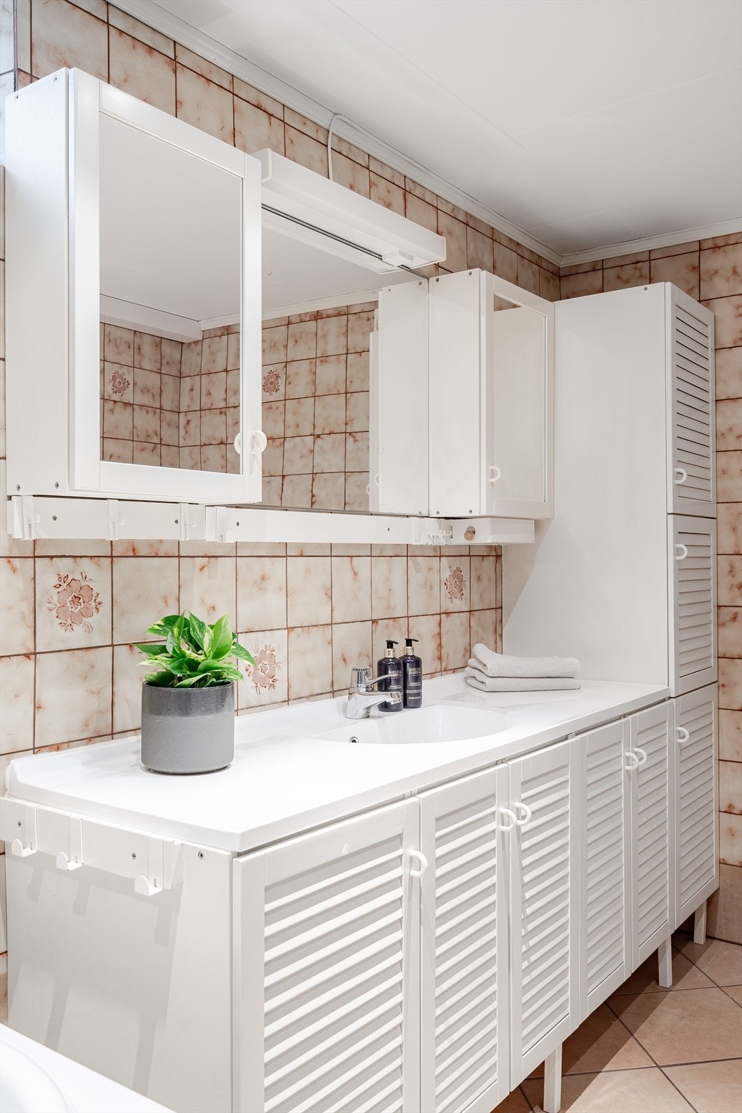 Lys innredning med god oppbevaringsplass, heldekkende servant og speil med belysning over. Galleribilde