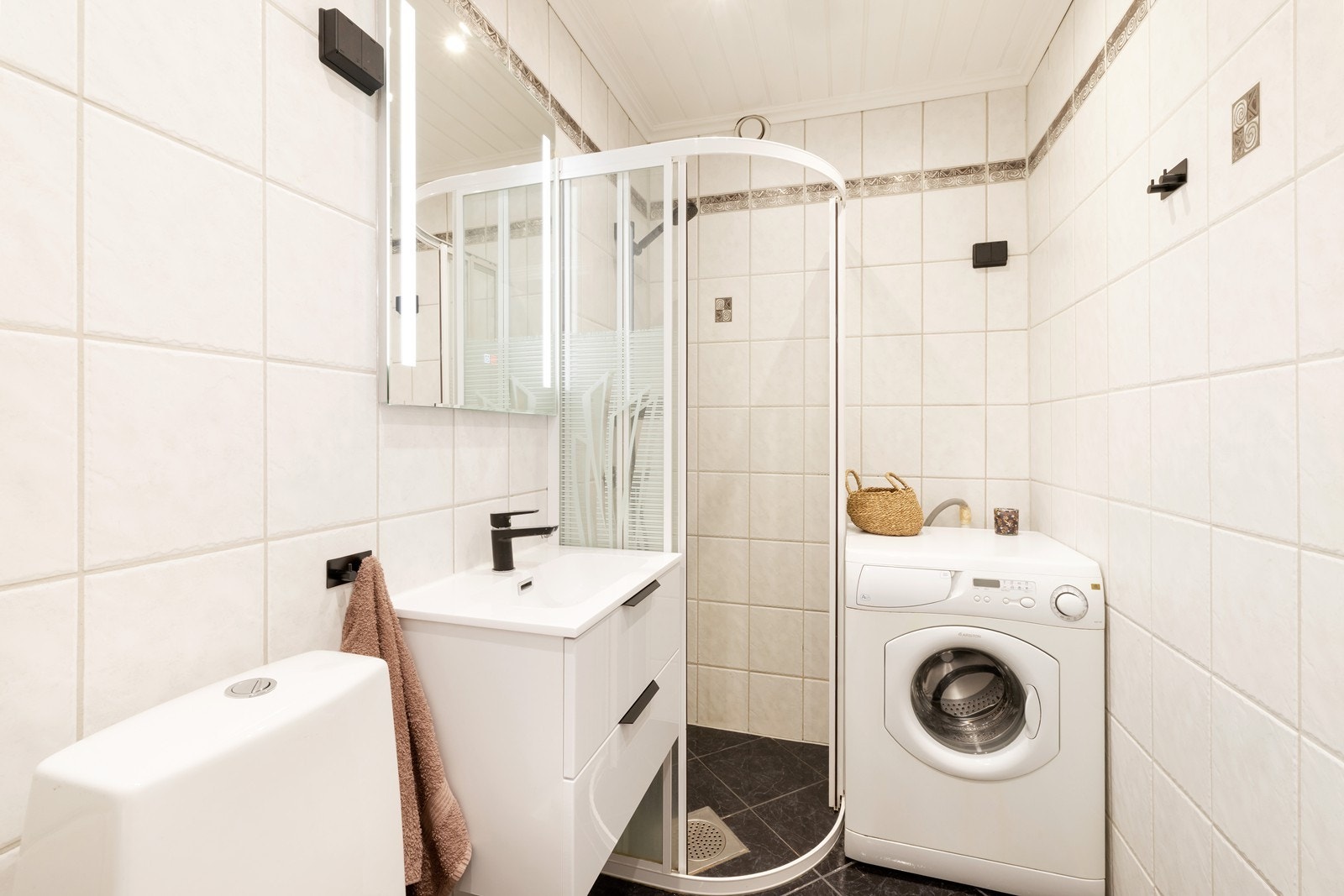 Pent flislagt bad med varme i gulv. Badet har dusjhjørne, toalett og servant med underskuffer samt opplegg til vaskemaskin. Vaskemaskin medfølger. Galleribilde