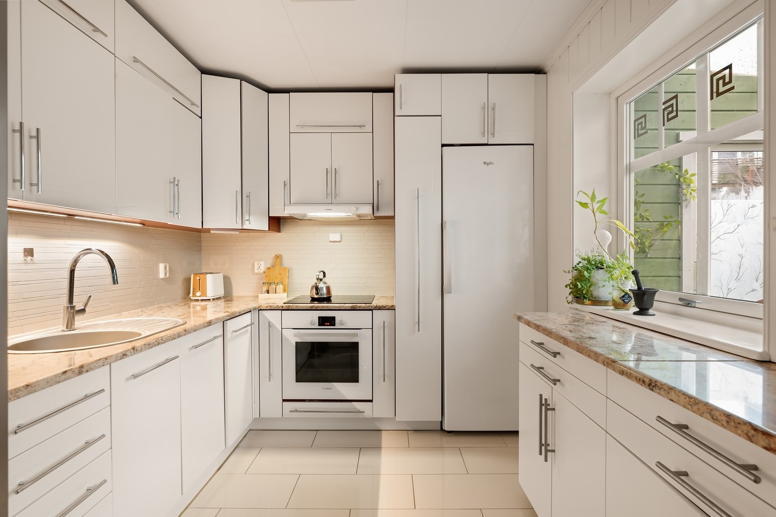 Stilrent kjøkken med steinbenkeplate og integrerte hvitevarer Galleribilde