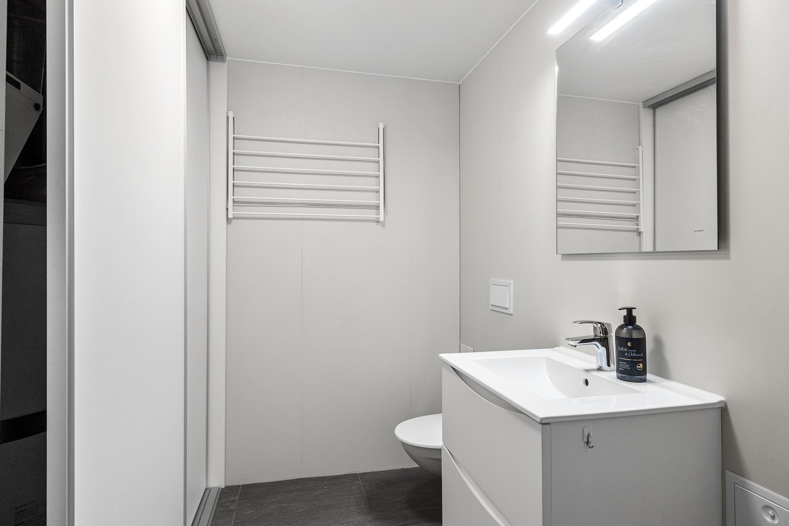 Rommet er innredet med servant, vegghengt toalett og opplegg for vaskemaskin og tørketrommel. I tillegg er det tilgang på gode lagringsmuligheter i skyvedørsgarderobe. Galleribilde