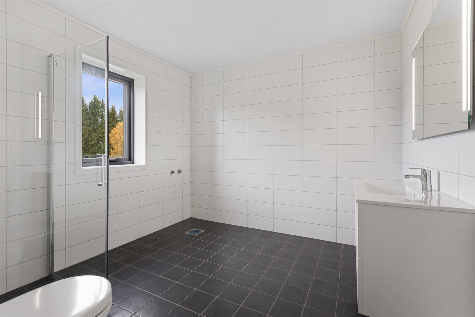 Bad i 2. etg. har vegghengt servantskap med heldekkende servant og ett-greps armatur, vegghengt toalett og dusjhjørne Galleribilde