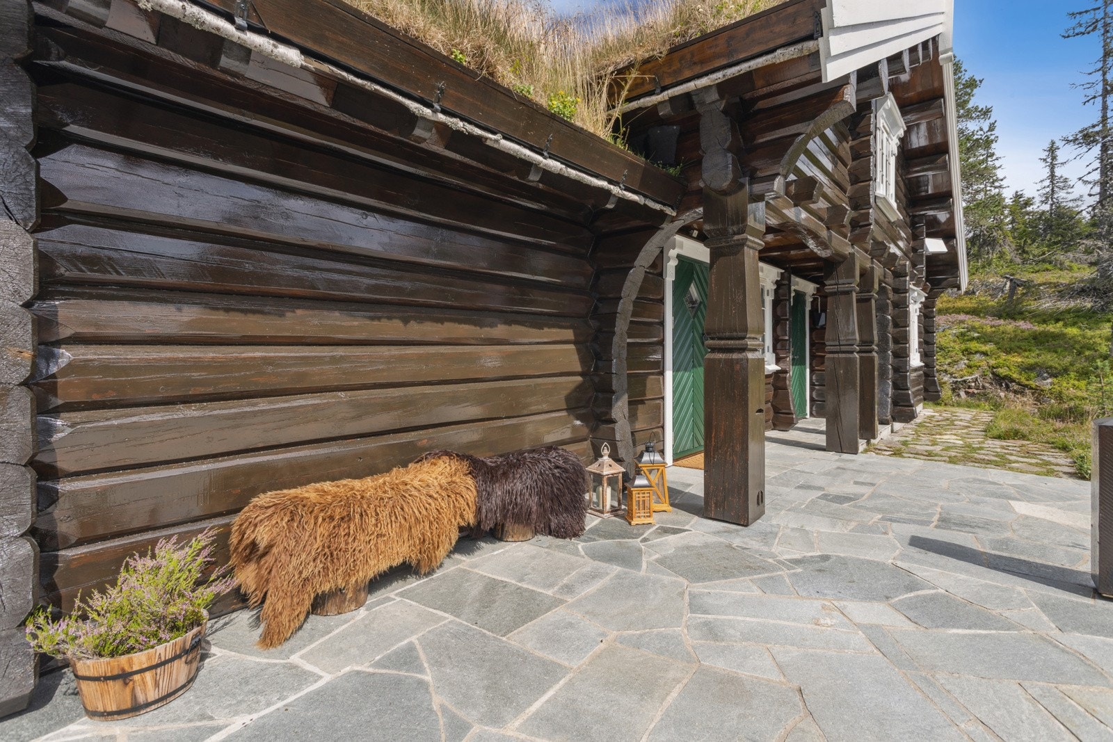 Ved inngangsparti er det skiferfliser på terrasse som strekker seg rundt to sider av hytta. Her ute er det nydelig utsikt og mange muligheter for utemøbler og utekos Galleribilde