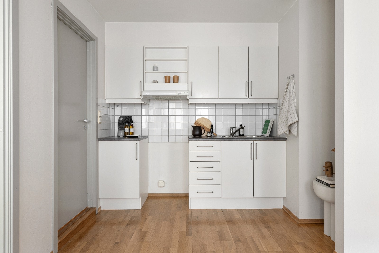 Innredningen er fra Sigdal, med hvite glatte fronter og grå, tykk laminatbenkeplate med nedfelt vaskekum i børstet stål Galleribilde