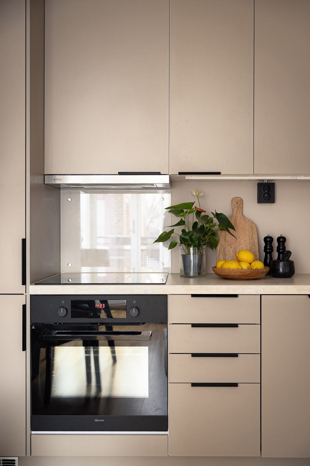 Moderne og tidsriktig kjøkken fra 2021 med glatte fronter, sprutplater montert på vegg bak koketopp og kum og laminert benkeplate. Galleribilde