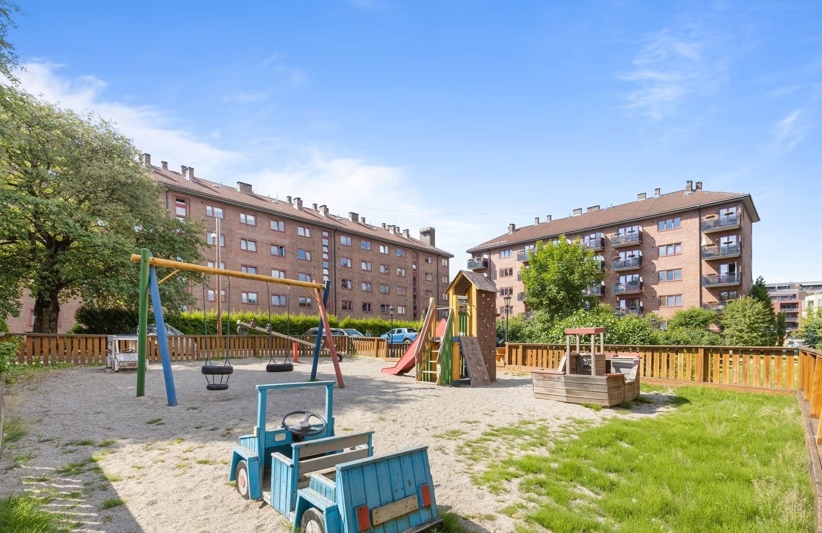 Stor, bilfri lekeplass for de minste med sandkasse, huskestativ og lekeapparat. Galleribilde