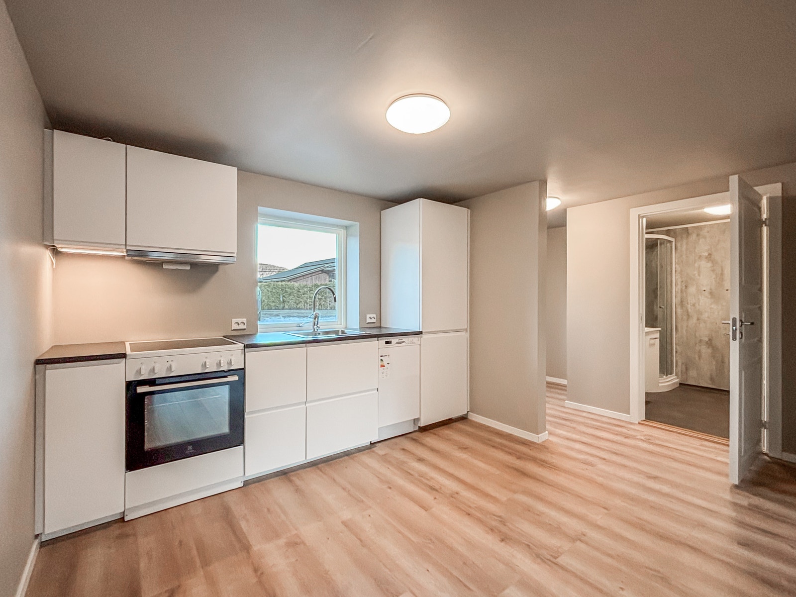 Pent og moderne kjøkken med slette hvite fronter og integrerte hvitevarer. Galleribilde