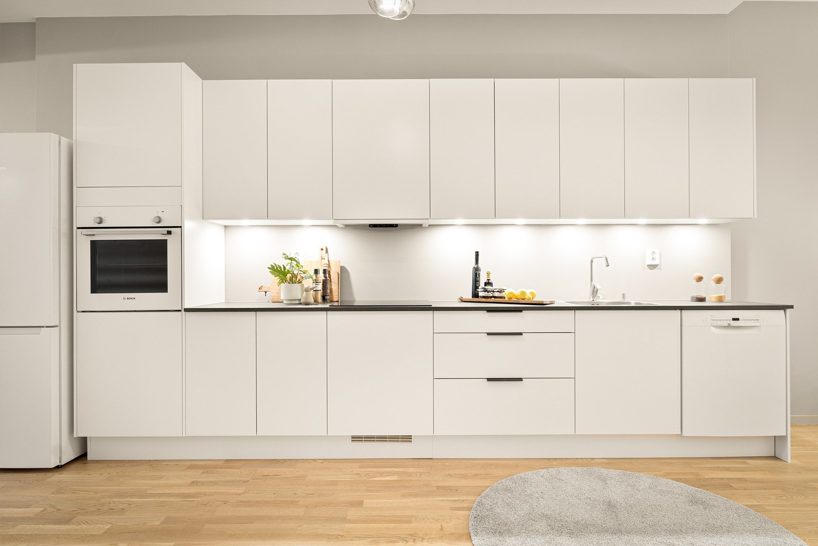 Flott kjøkkeninnredning levert av Sigdal med slette fronter. Innredningen er utstyrt med platetopp, oppvaskmaskin, stekeovn og kombiskap levert av Bosch. Galleribilde