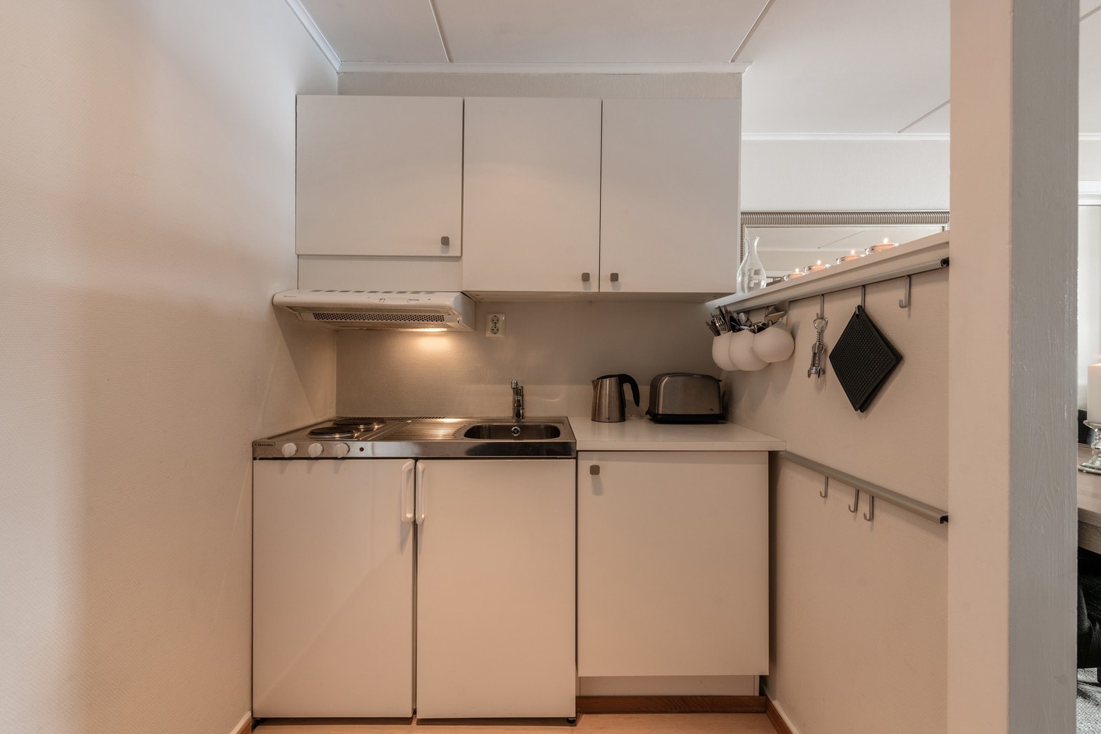 Montert hybelkjøkken med integrert kjøleskap, kokeplater og vask av rustfritt stål. Galleribilde