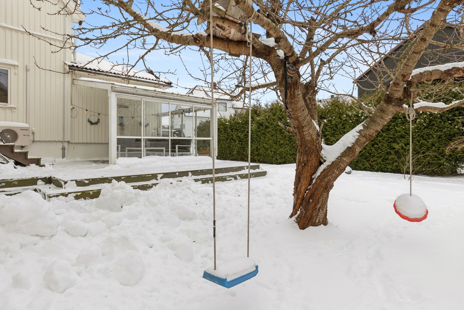 Flere flotte terrasser og pergola i en etablert hage med plen, hekk, frukttre og mye sol. Galleribilde