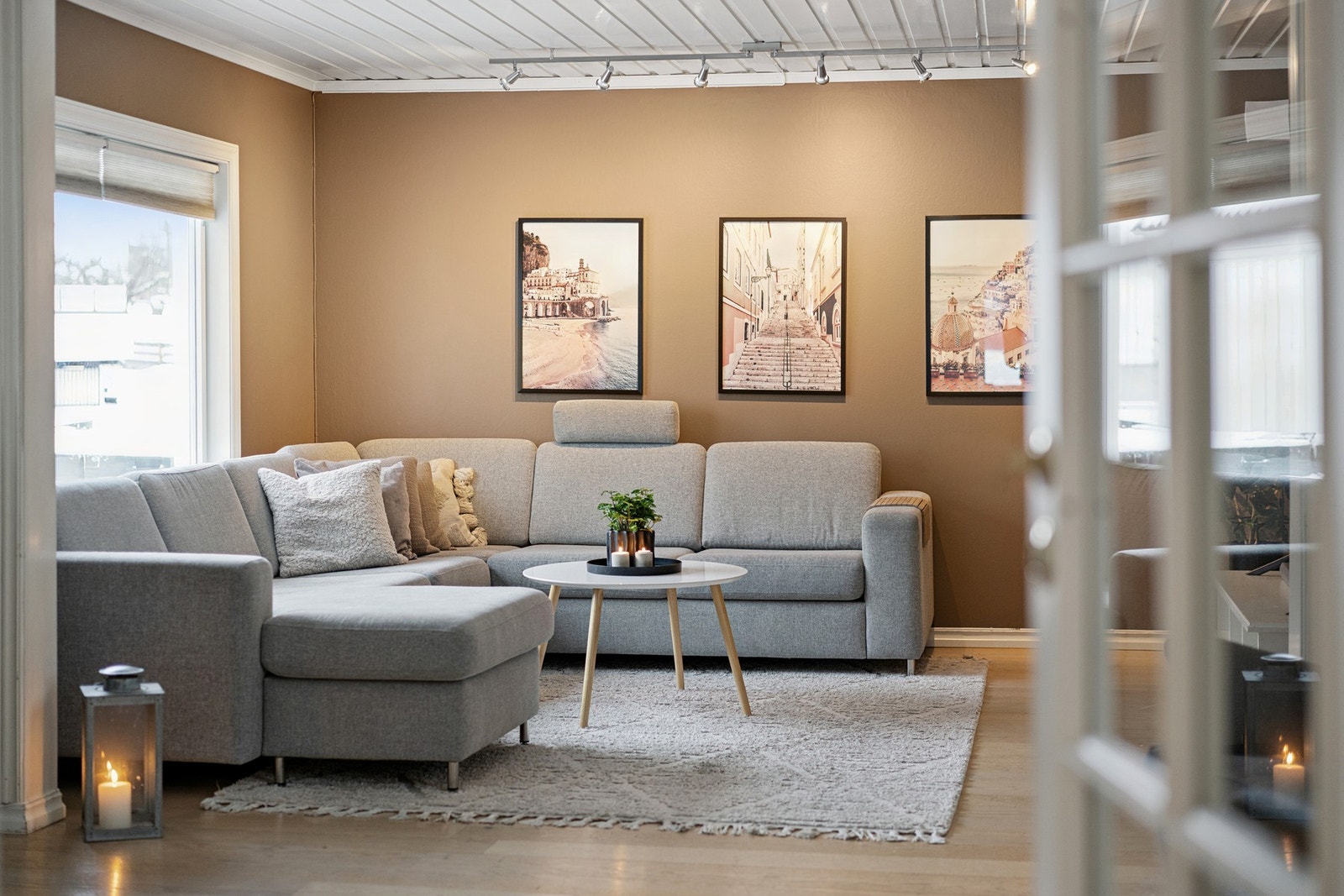 Stuen har naturlige soner for både TV-krok og sittegrupper, med lun stemning og lyse overflater. Galleribilde