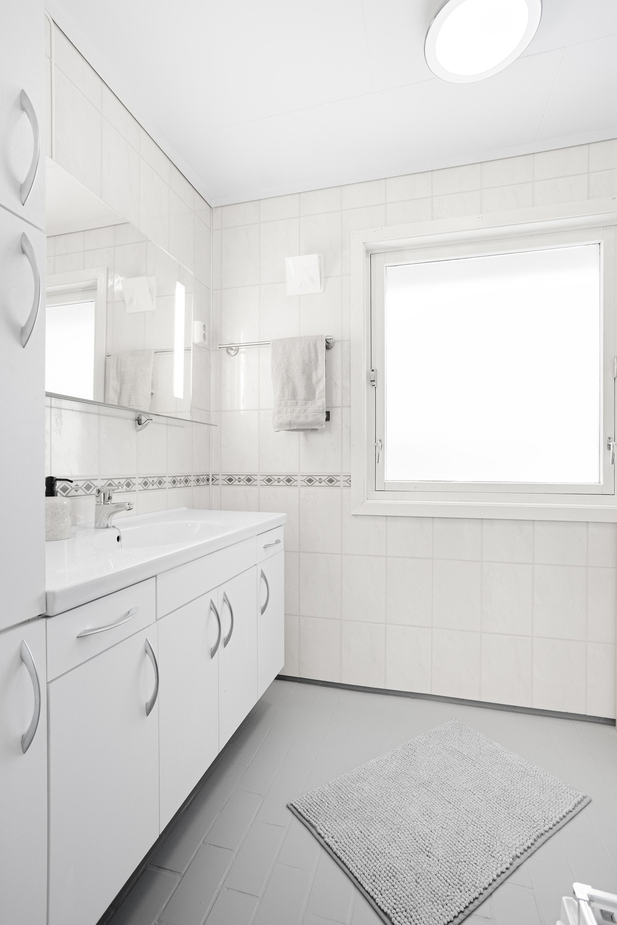 Romslig bad i 1.etg. badet har dusjkabinett og varmekabler. Den øvrige innredningen består av heldekkende servant med hvite underskap, et matchende veggskap og et speil med integrert belysning. Galleribilde