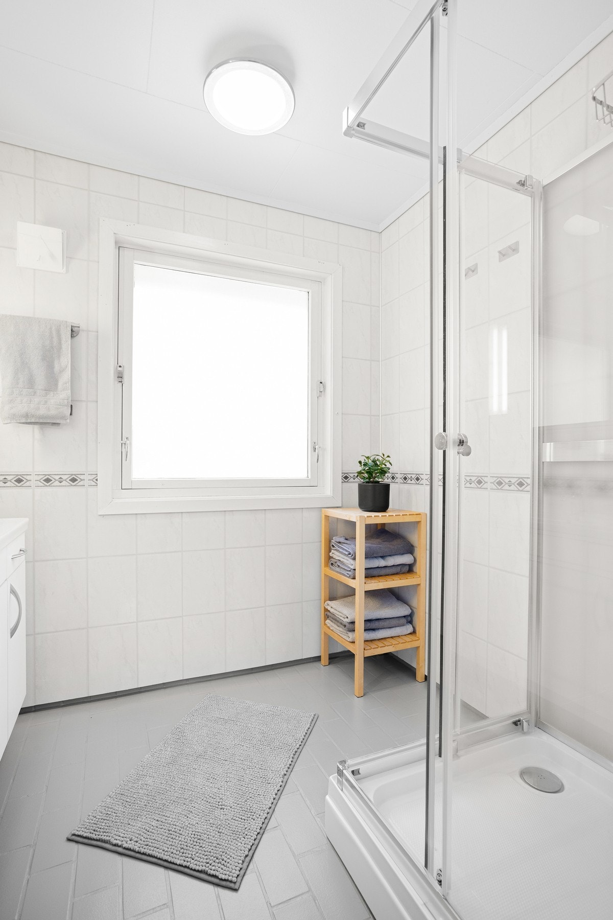 Romslig bad i 1.etg. badet har dusjkabinett og varmekabler. Den øvrige innredningen består av heldekkende servant med hvite underskap, et matchende veggskap og et speil med integrert belysning. Galleribilde