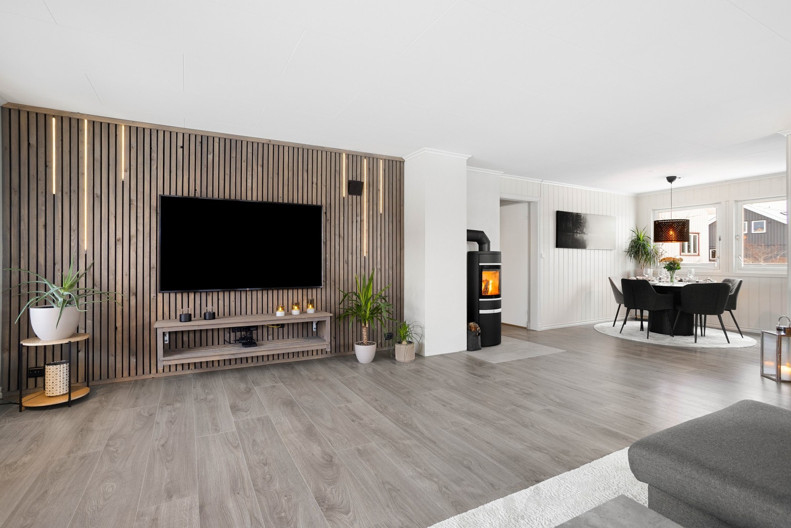 En trendy spilevegg med innfelt belysning gir ekstra liv og lys til rommet. Stuen er naturlig inndelt i ulike soner, og det passer utmerket å innrede med spisebord nærmest kjøkkenet. Galleribilde