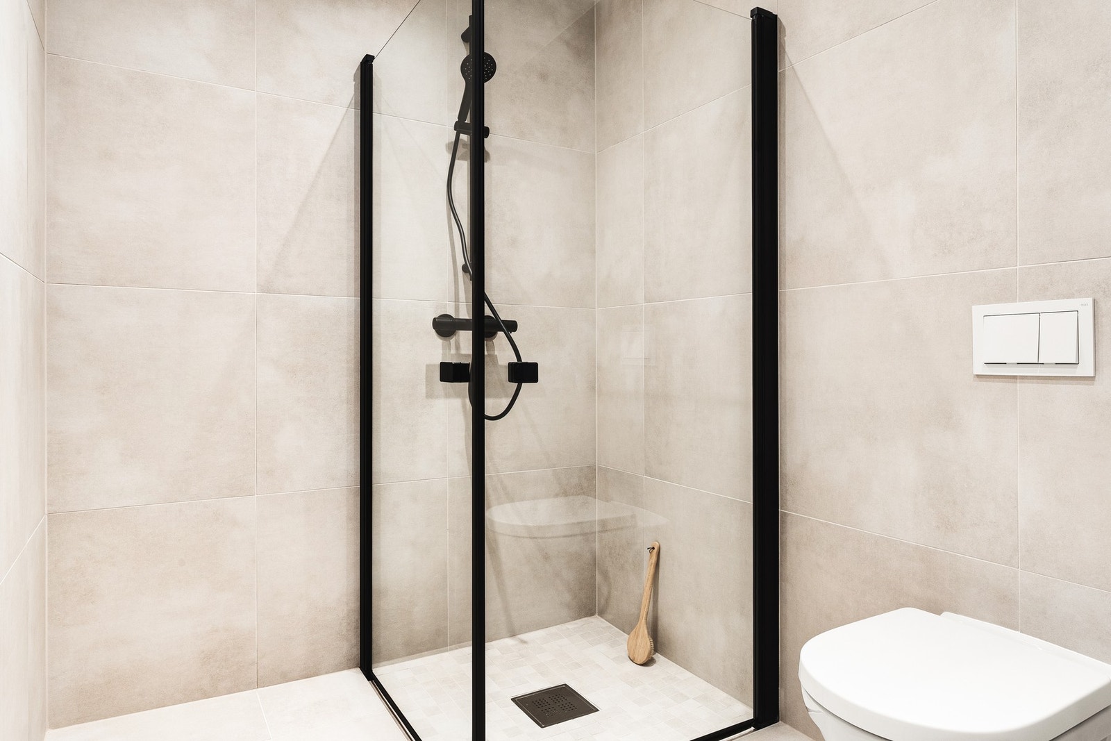 Begge badene er helflisede med moderne fargetoner, sorte detaljer, dusjhjørne og varmekabler i gulv. Galleribilde