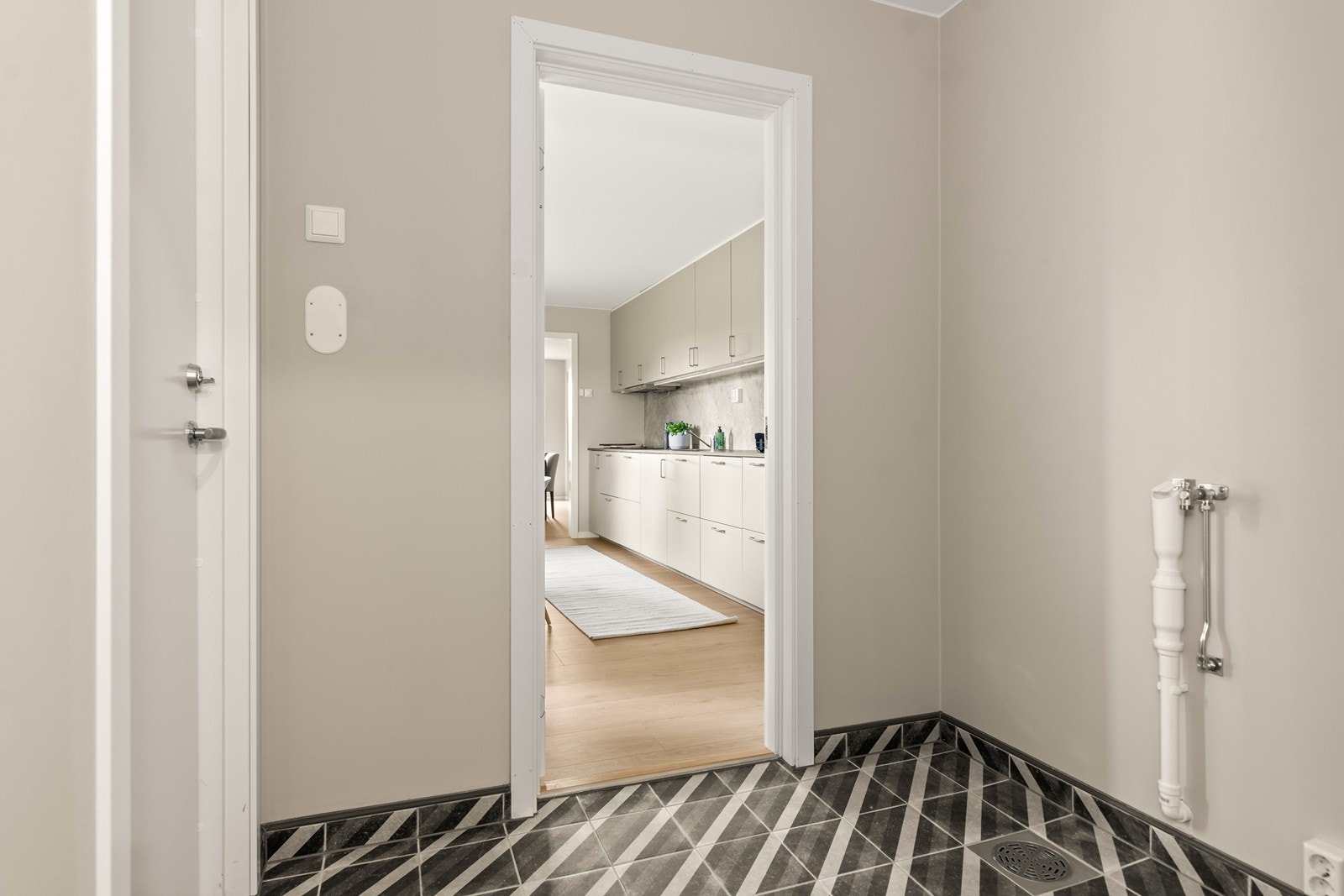 Innenfor kjøkkenet ligger et separat vaskerom med flislagt gulv og malte flater på veggene. Det er opplegg for vaskemaskin og sluk i gulvet. Her er det dessuten egen bi-inngang, rett inn til vaskerommet Galleribilde