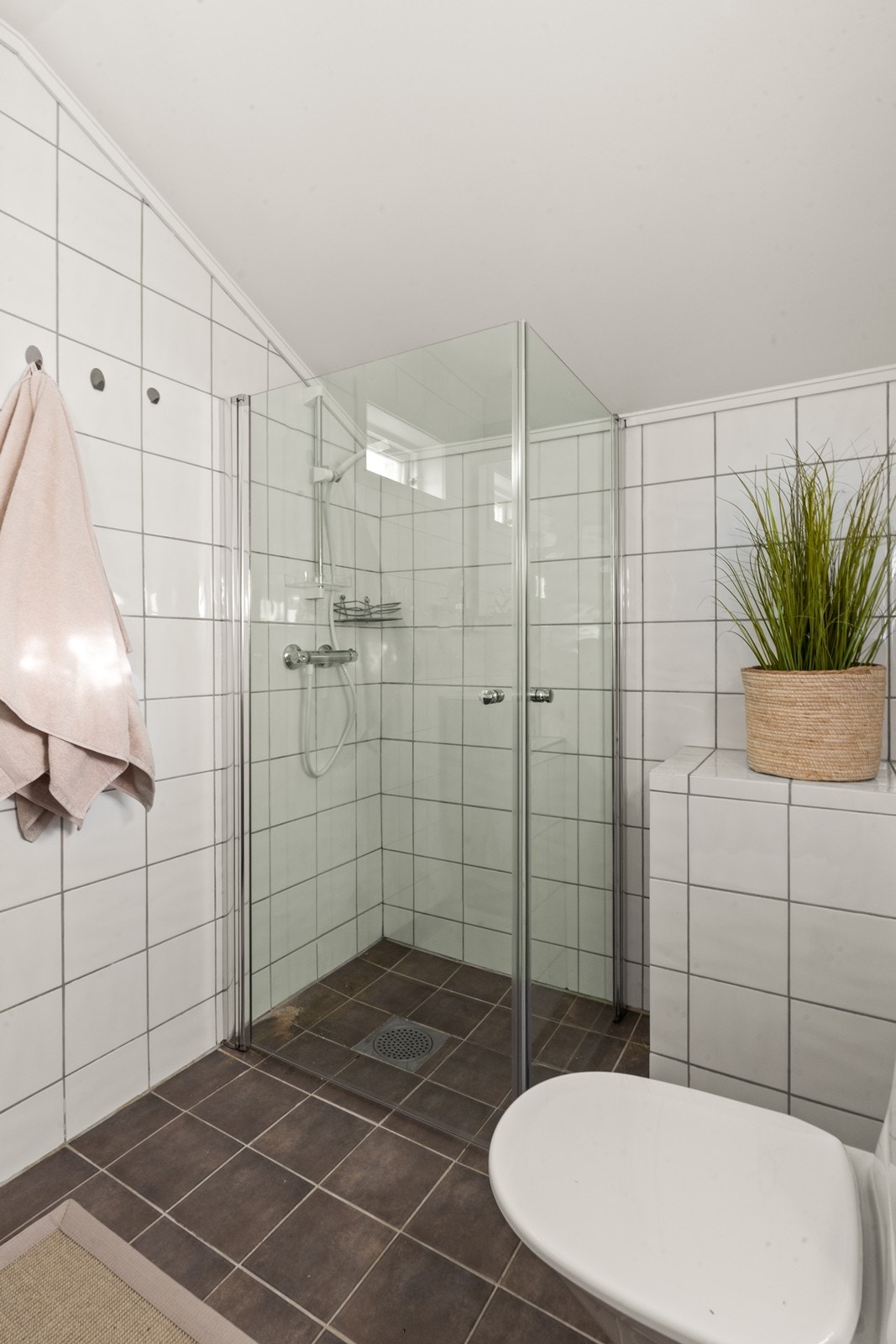 Videre er det dusjhjørne med glassdører, i tillegg er det gulvmontert wc Galleribilde