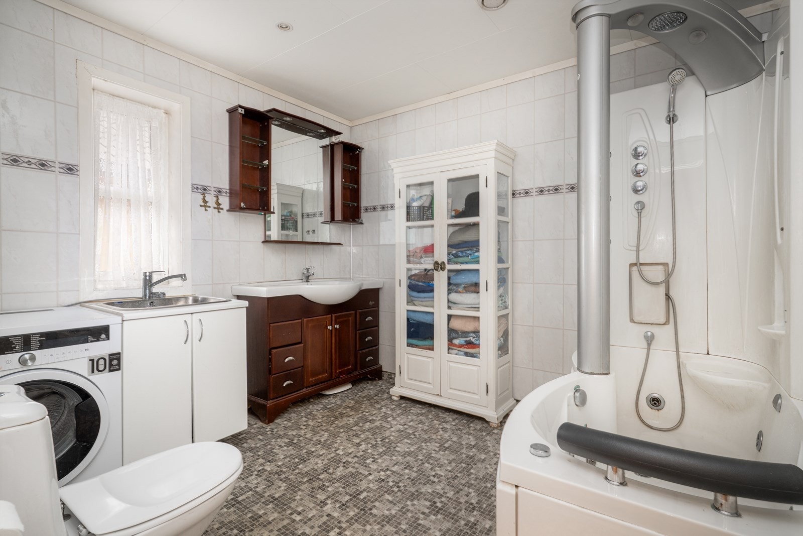 Kombinert bad- og vaskerom i hovedetasjen, med standard fra byggeår. Badet har varmekabler i gulv og innfelte spotter i tak. Galleribilde