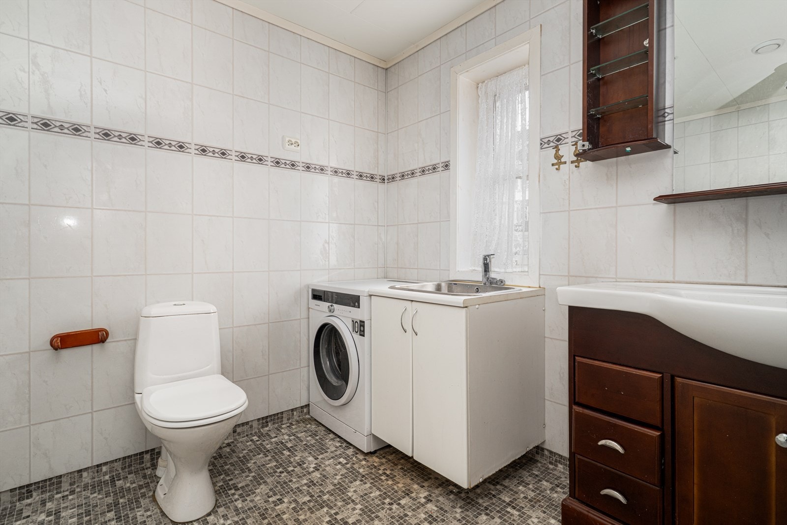 Videre er badet utstyrt med toalett, servantinnredning og opplegg vaskemaskin, samt badekar/dusjkabinett og utslagskum i stål. Galleribilde