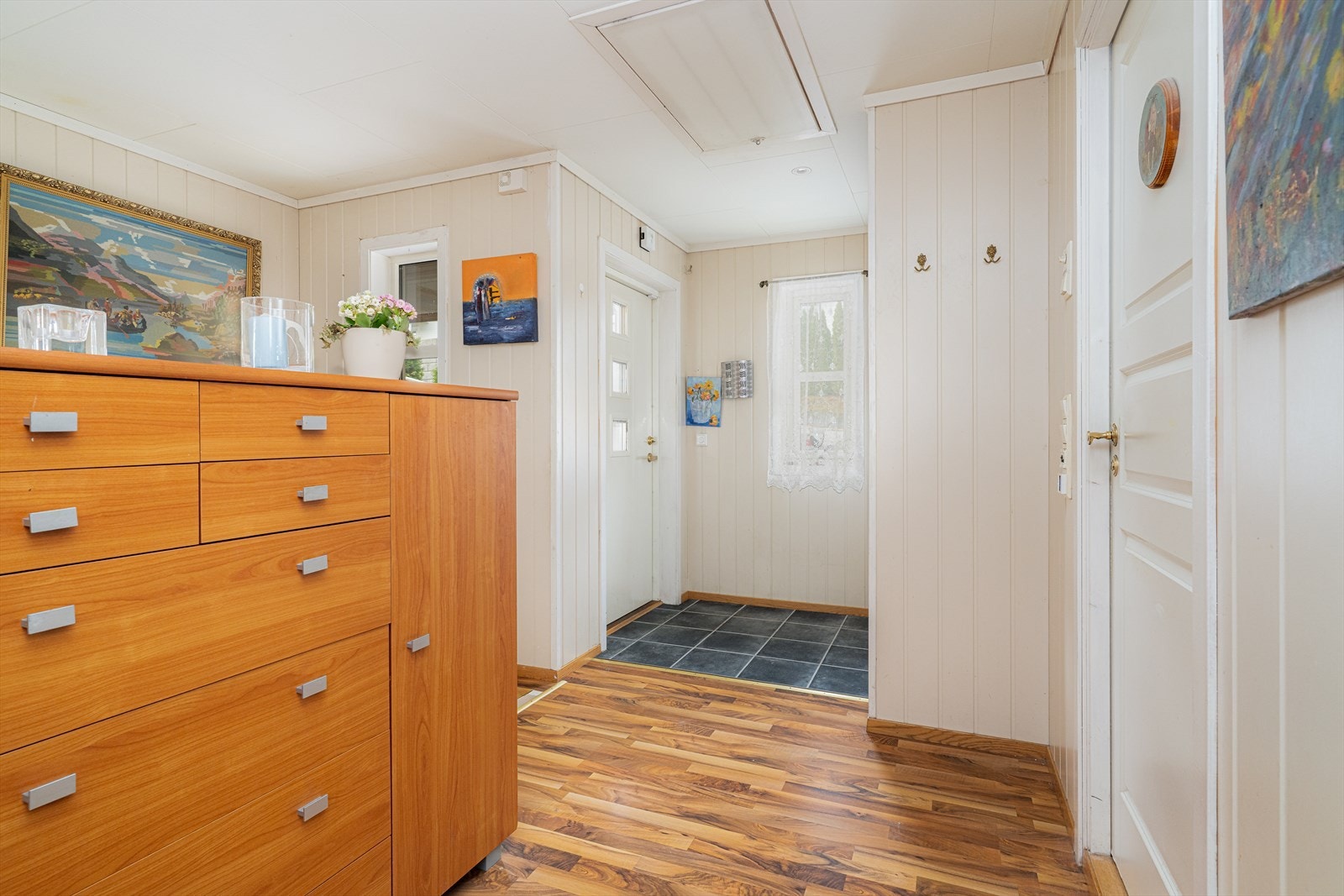 Lys entré med flislagt gulv og praktisk garderobeskap. Åpent til tilliggende trappegang med lyse overflater og loftsluke i tak. Galleribilde