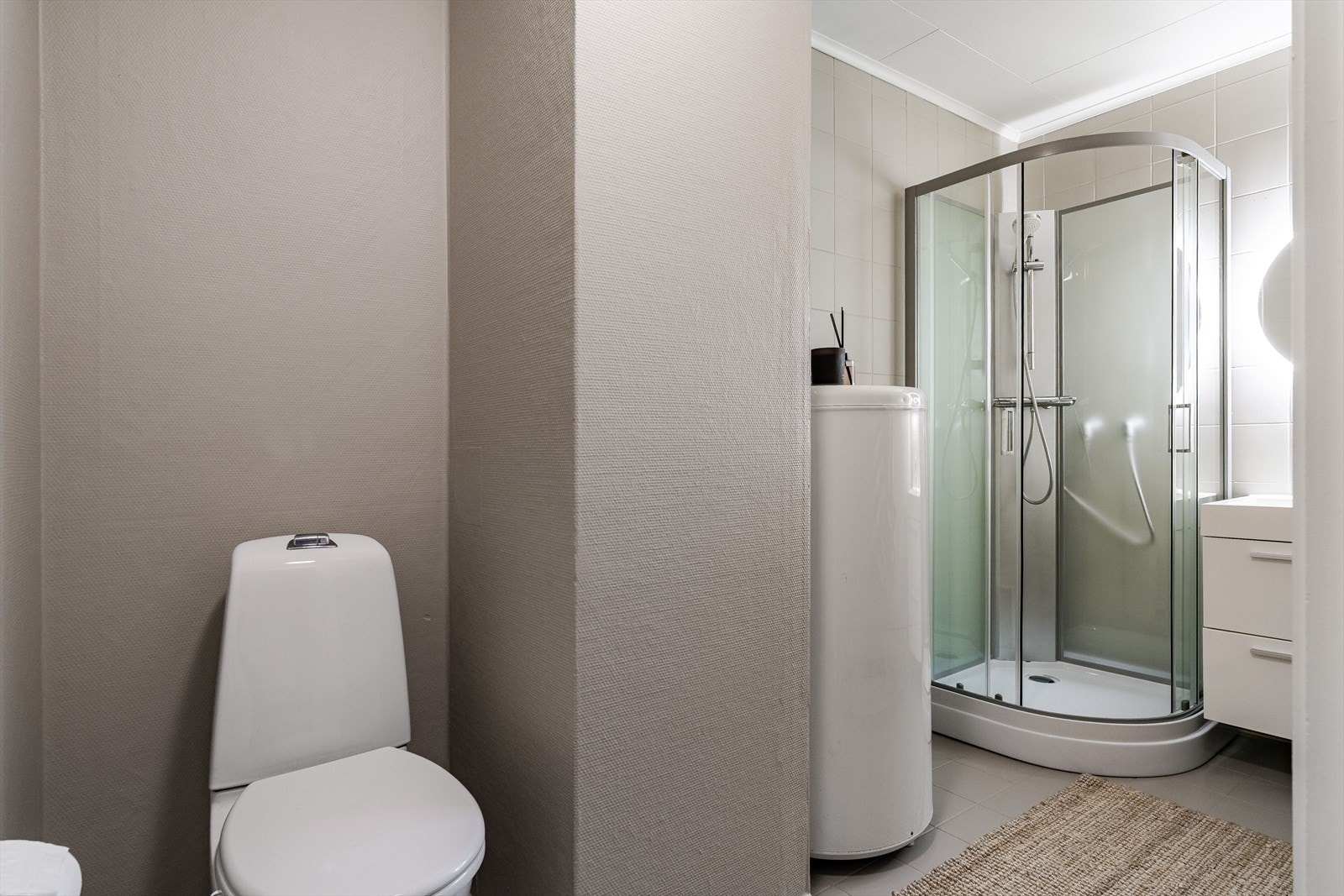 Badet består av toalett, dusjkabinett, servantskap og lysspeil. Galleribilde