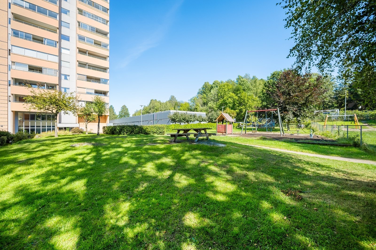 Fellesområder sommerstid | Fellesområdene er opparbeidet med sittegrupper, lekeplasser, beplantning, trær, ballbinge og grønrområder Galleribilde