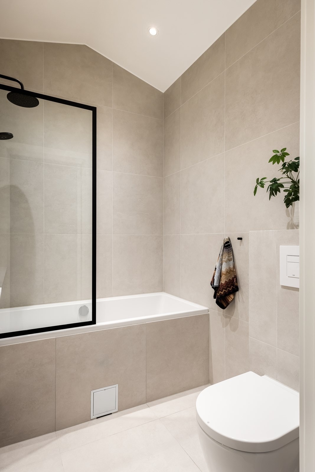 Badet har innebygd badekar med glassvegg, vegghengt wc og servant med underskap Galleribilde