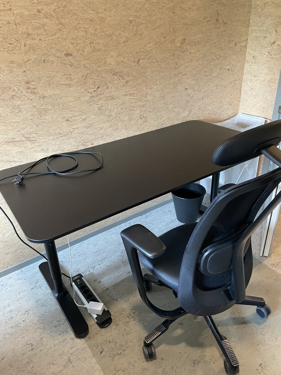 Fin kontorstol og stor pult, skjøteledning, søppelbøtte Galleribilde