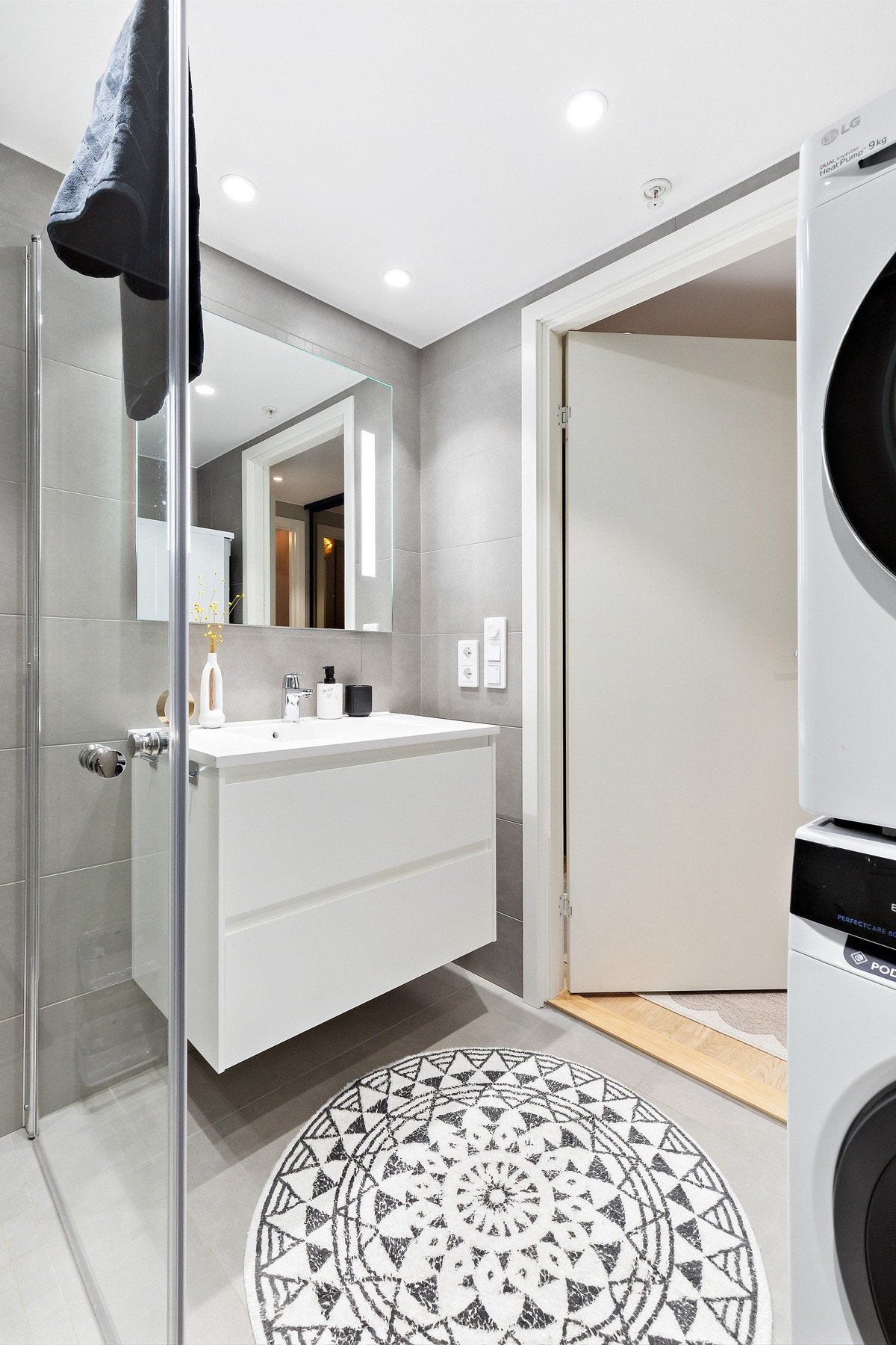 Badet er helfliset med plass til vaskemaskin og tørketrommel. Hvit, tidløs baderomsinnredning. Galleribilde