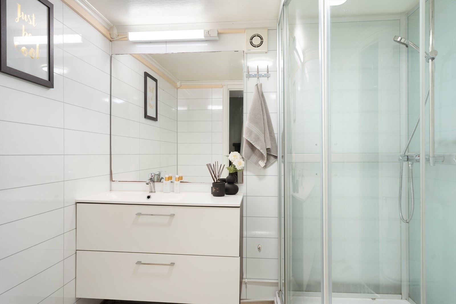 Lyst baderom innredet med vask i seksjon, dusj og wc. Galleribilde