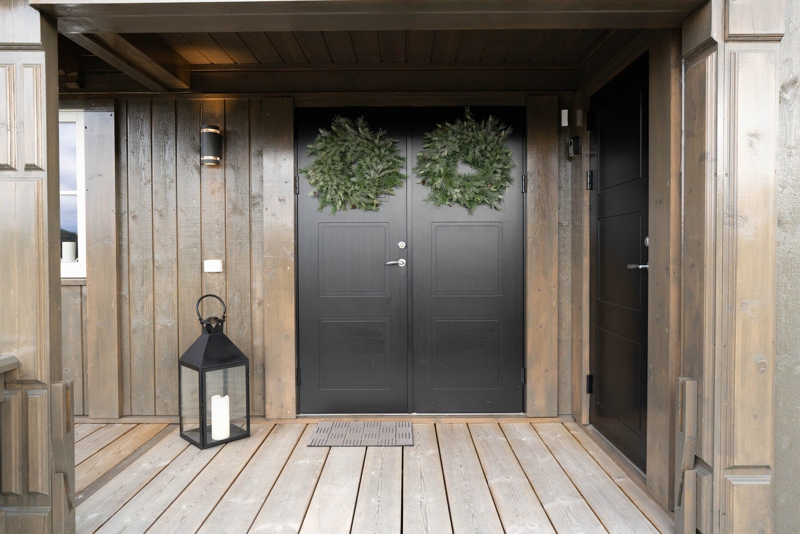 Hyggelig delvis takoverbygget inngangsparti med to-fløyet inngangsdør. Døren til høyre tar deg inn i den utvendige boden. Foto: Uthus Photography v/Pål Harald Uthus. Galleribilde