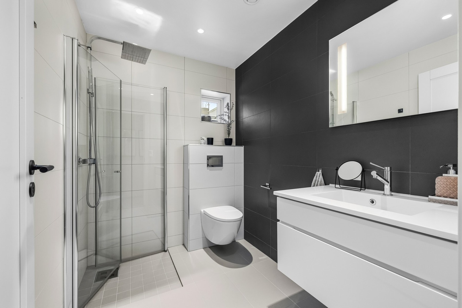 Boligens andre baderom ligger også i 1.etasje og er et delikat bad med gulvvarme, downlights, vegghengt toalett og romslig dusjhjørne med regnfallsdusj og innfellbare glassdører. Galleribilde